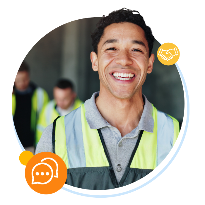 Worker smiling at the camera while coworkers collaborate on a job site