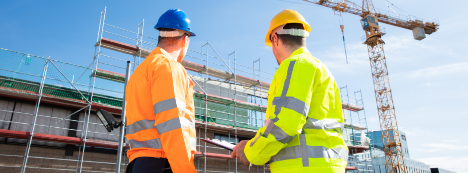 Project manager and field safety officer reviewing inspection checklists and mobile forms on a job site, discussing pain points and must-have features for new safety software.