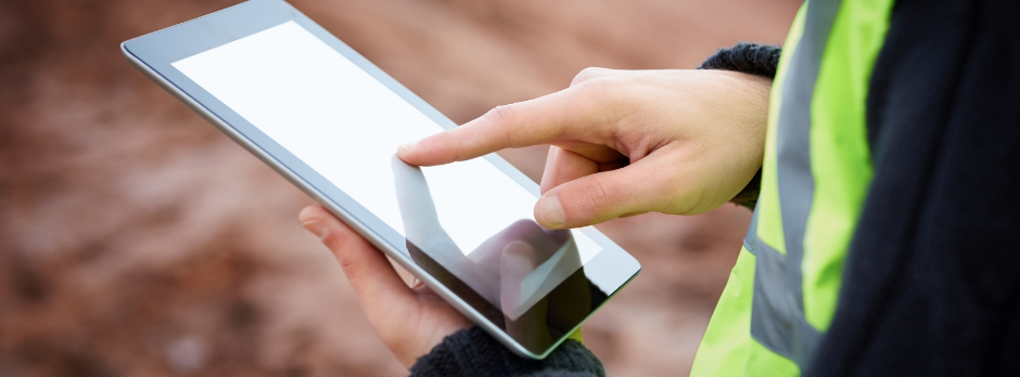 A safety consultant using a mobile device to monitor real-time safety data on-site, ensuring compliance and workplace security.