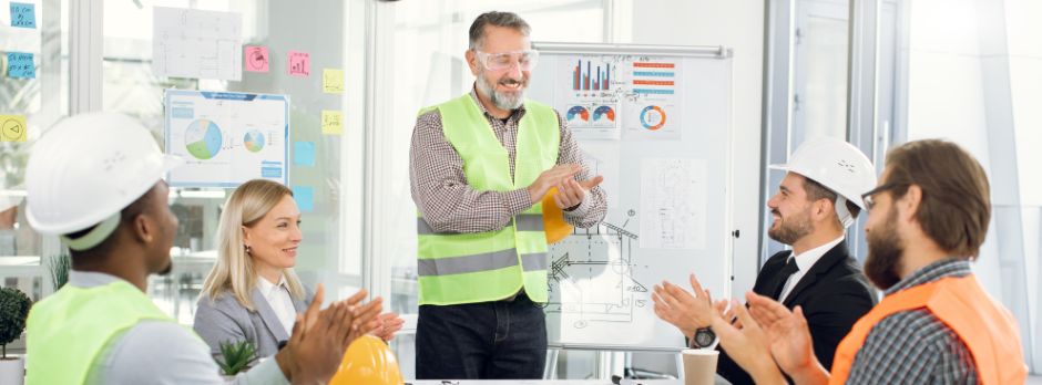 A safety officer in a high-visibility vest leading a team discussion on a tablet, symbolizing internal champions guiding successful software rollouts in high-risk industries.